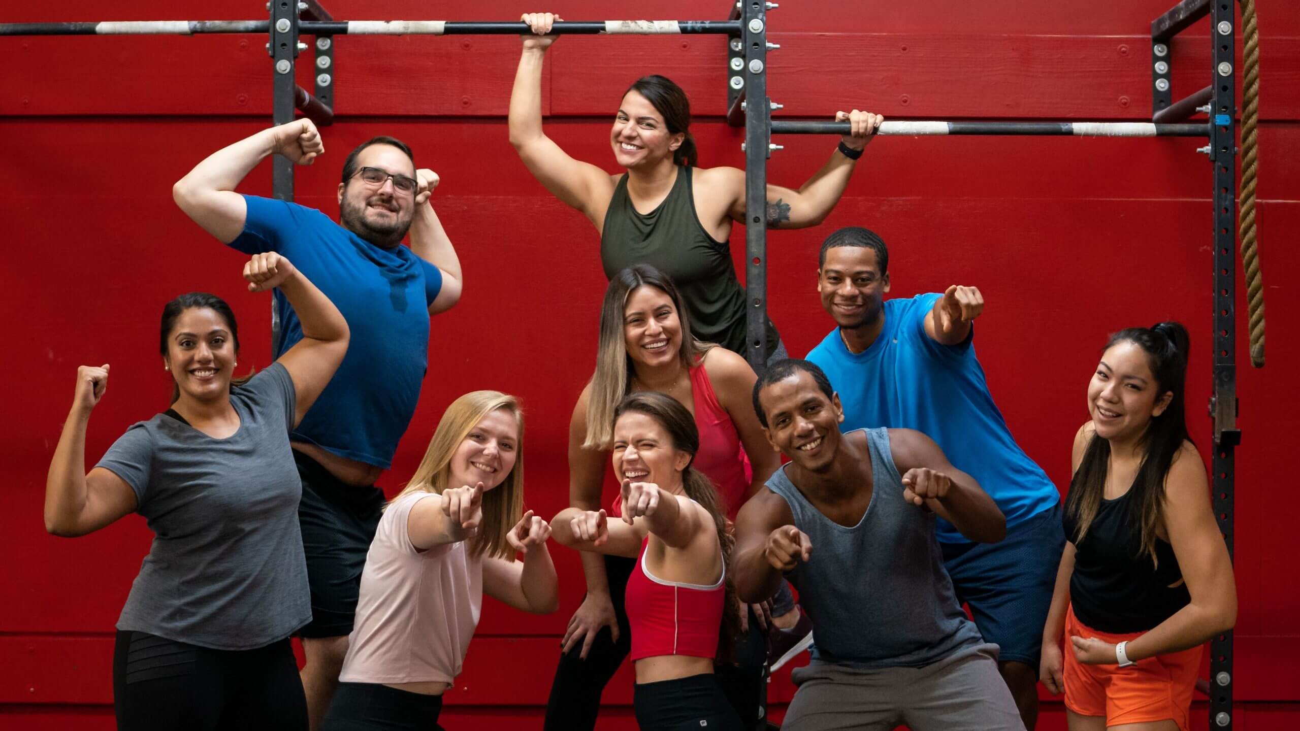 Adult members pose together in front of a red wall, every face in the frame.